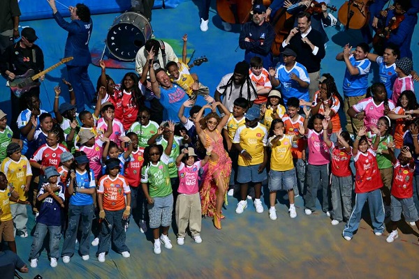 Colombian singer, songwriter and producer Shakira (C), Nigerian singer, songwriter, and record producer Burna Boy and US actor Jason Sudeikis gesture with performers at the Half Time Show during the 2026 World Cup football tournament final match between Spain and Argentina at the New York/New Jersey Stadium in East Rutherford on July 19, 2026.  (Photo by MAURO PIMENTEL / AFP via Getty Images)